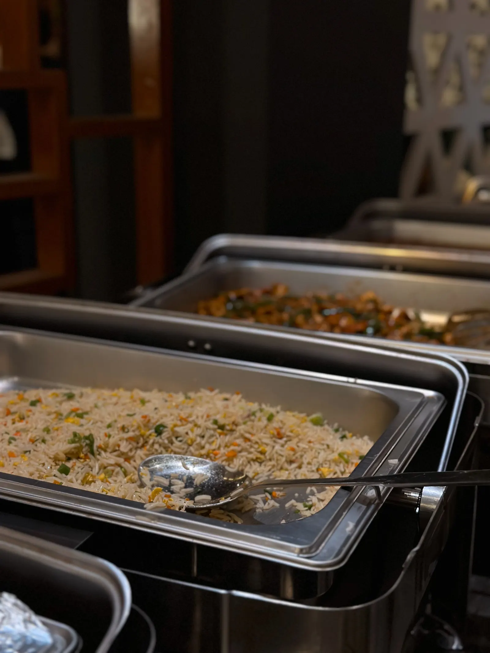 Steel catering trays of rice and vegetables in a kitchen